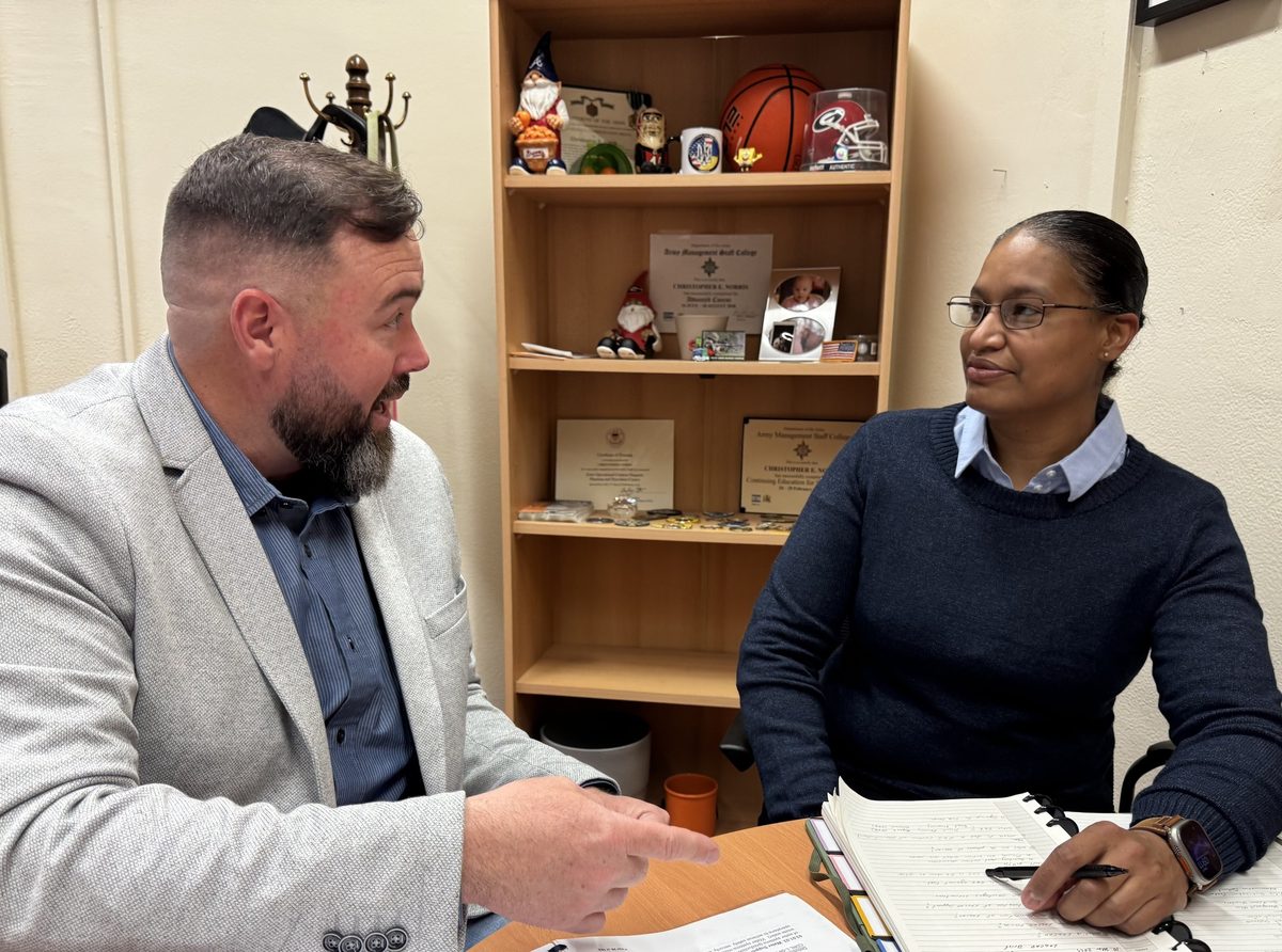 A civilian logistics leader mentors Master Sgt. Karina Rodriguez across a desk during her DoD SkillBridge internship before her retirement.