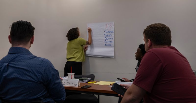 Service members in a Transition Assistance Program class at Moody Air Force Base, Georgia, list job-search websites together on a poster.
